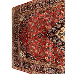 Persian Ardakan crimson ground rug, the field with shaped floral design medallion surrounded by curled leafy branches, scrolling border with stylised plant motifs