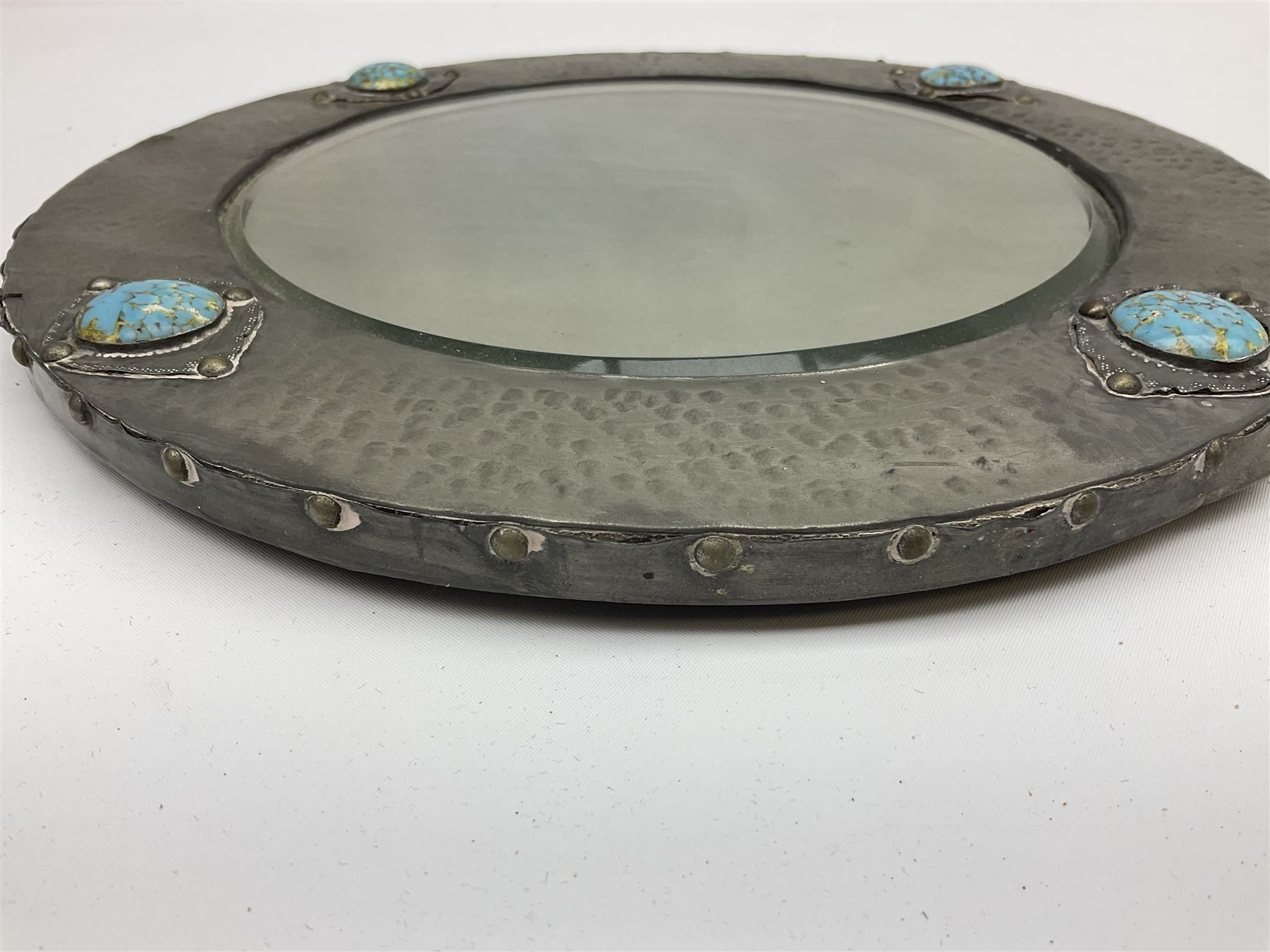 Arts & Crafts style circular hammered pewter mirror inset with four turquoise cabochons, D27.5cm
