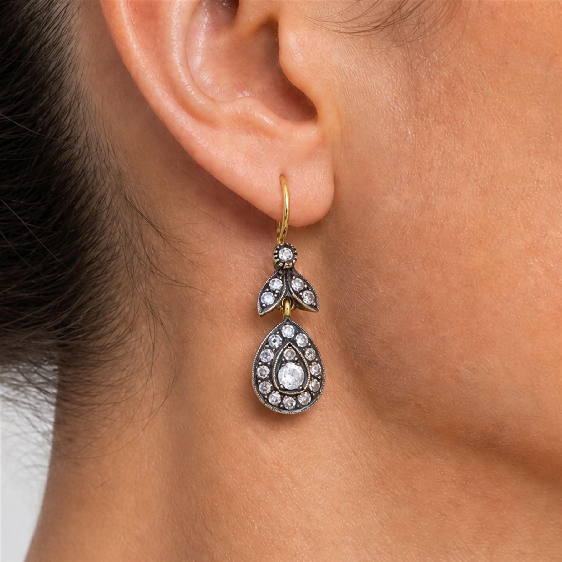 Pair of gold and silver diamond earrings, each pendant with pear shaped drop set with round brilliant cut and single cut diamonds, suspended from a diamond set leaf design bail, total diamond weight approx 1.00 carat