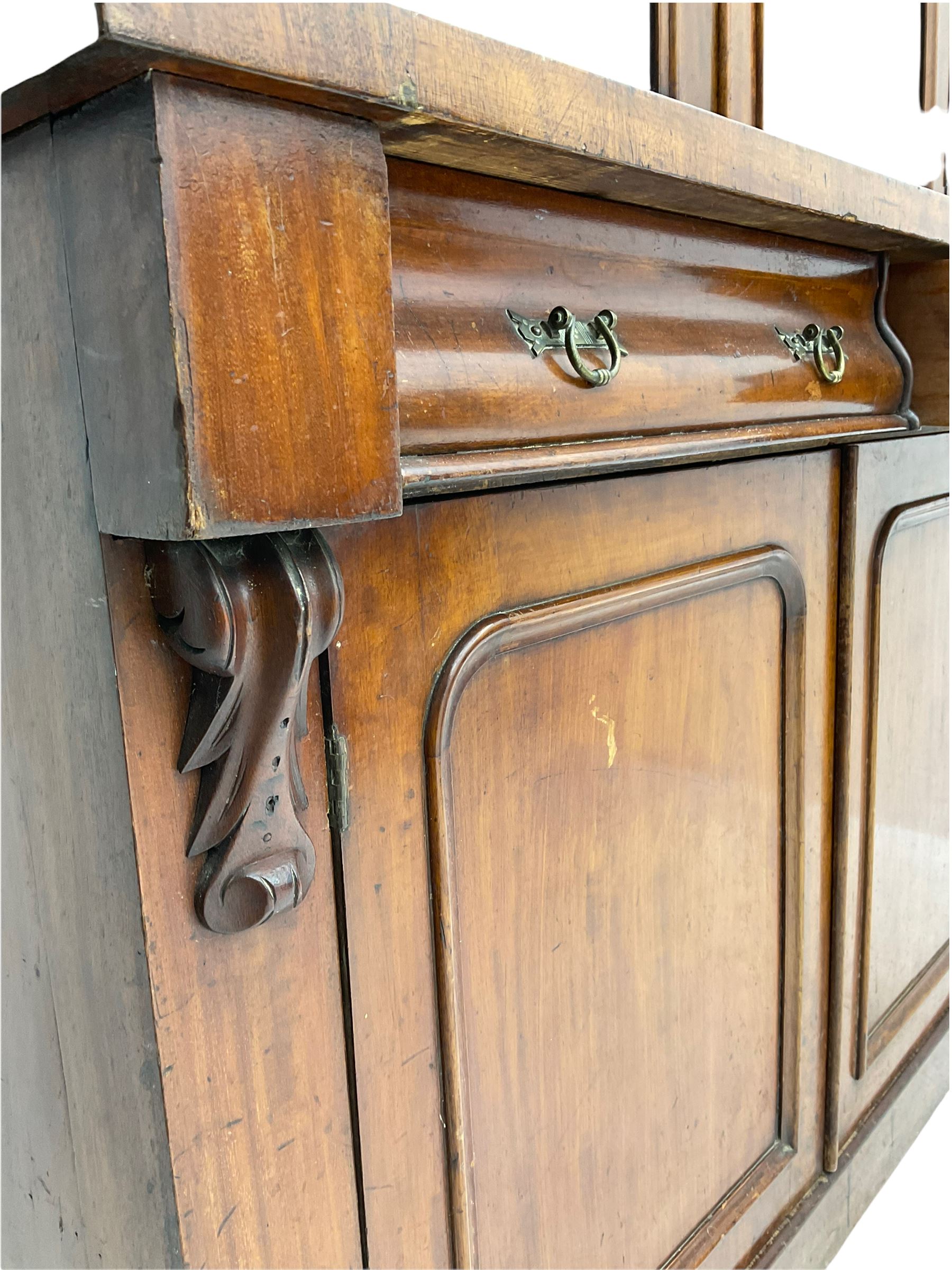 Victorian mahogany bookcase on cupboard, projecting cornice over two glazed doors and carved corbels, fitted with two drawers and double cupboard, plinth base