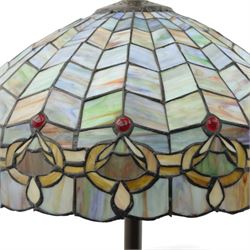 Late 20th century Tiffany style standard lamp, the leaded glass domed shade composed of geometric panels in mottled pastel tones, bordered by stylised foliate motifs and coloured cabochons, raised on a spiral twist metal column and circular moulded base