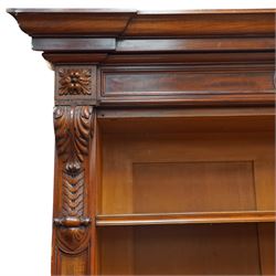 Large early 19th century Country House mahogany breakfront library bookcase, the projecting moulded cornice over a frieze applied with carved flowerhead paterae, the open panelled upper section fitted with adjustable shelves and shaped valances, divided by moulded pilasters with acanthus-carved corbels, the projecting base enclosed by eight panelled cupboard doors with central turned canted pilaster, on plinth base