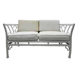Late 20th century faux bamboo conservatory sofa, white painted frame with geometric openwork back and sides, loose cream cushions, on cylindrical supports (W134cm, D76cm, H80cm); matching armchair (W75cm, D76cm, H80cm); matching coffee table with glass insert (W46cm, D45cm, H36cm)
