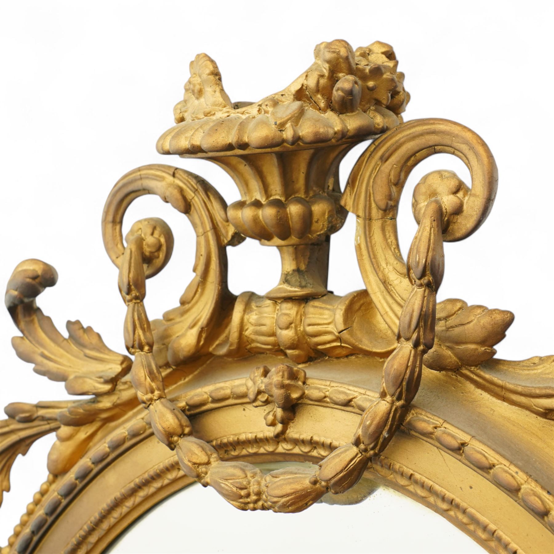 Late 19th century Louis XVI style giltwood and gesso girandole oval wall mirror, the oval frame surmounted with stylized urn finial and ribbon-tied garlands, laurel swags and rosettes, egg and dart decorated inner moulding and linked acorn outer moulding, flanked by intertwined foliate decorated candle branches 