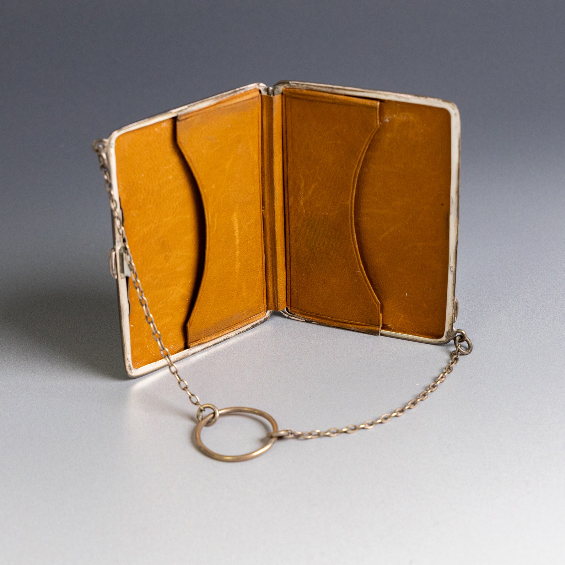 Early 20th century silver coin purse, with floral decoration and finger chain, hallmarked together with an early 20th century cigarette case,  with engraved initials, hallmarked and a silver filigree cigarette case
