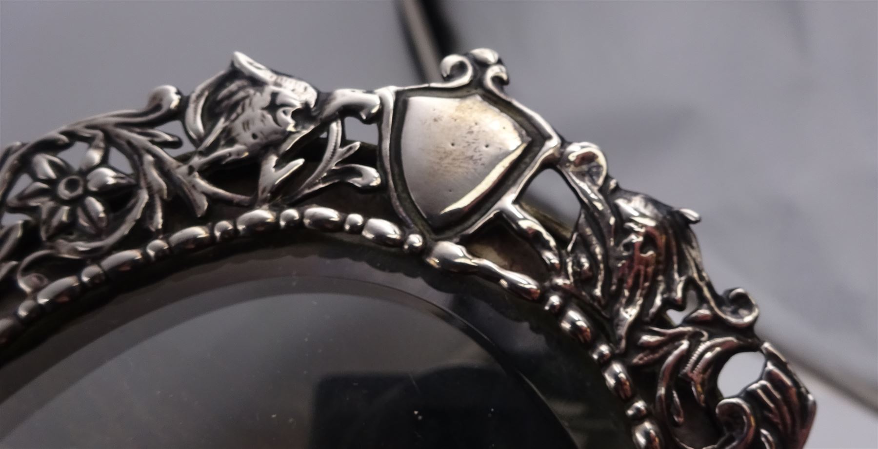 Continental silver miniature dressing table/wall mirror, of oval form with bevelled mirror plate, surrounded by a bead and dart rim, with pierced scrolling floral border with a standing cavalier to either side and the bust of a cavalier to the base, H17.7cm