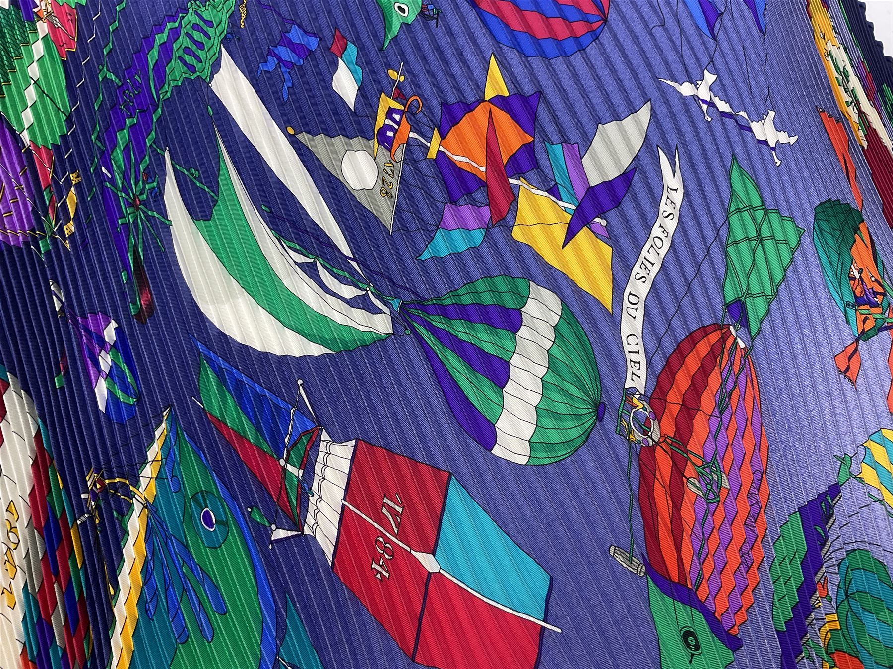 Hermès 'Les Folies Du Ciel' plisse silk scarf, designed by Loïc Dubigeon, printed with hot air balloon motifs, contained within twisted green rope border, on merging light and navy blue ground, with rolled hand stitched edges and Hermes material label, length 129cm