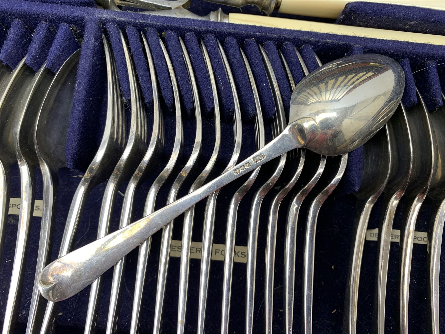 Late 19th/early 20th century composite canteen of silver flatware, contained within an early 20th century mahogany serpentine fronted case with twin drop carry handles, and hinged cover with boxwood stringing and central inlaid shell motif, above a single drawer with twin ring handles and Wellington style locking system, the cover and drawer opening to reveal plaque for Spink & Sons Ltd London, and fitted interior containing ivory handled knives, ivory handled carving set, and silver Hanoverian and Old English pattern cutlery, each with engraved monogram to terminal, hallmarked London, makers Spink & Son (John Marshall Spink), Goldsmiths & Silversmiths Co, and Chawner & Co (George William Adams), various dates ranging 1880-1923, gross weighable silver 92.59 ozt (2880 grams)