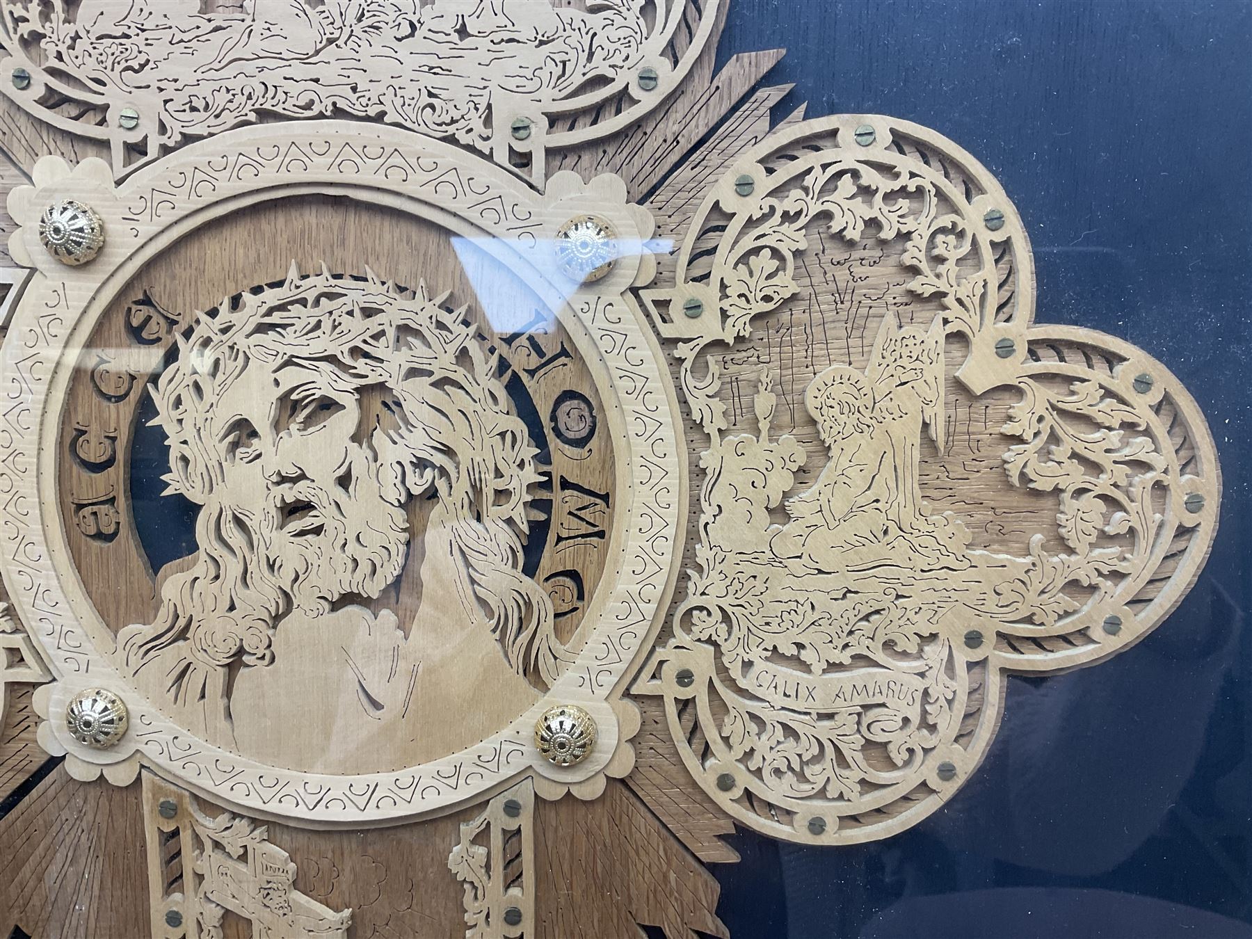 Cork carving of a religious cross depicting intricate scenes of various religious figures and motifs amongst trees and foliage, with central circular panel of Jesus Christ, in glazed frame, H95cm