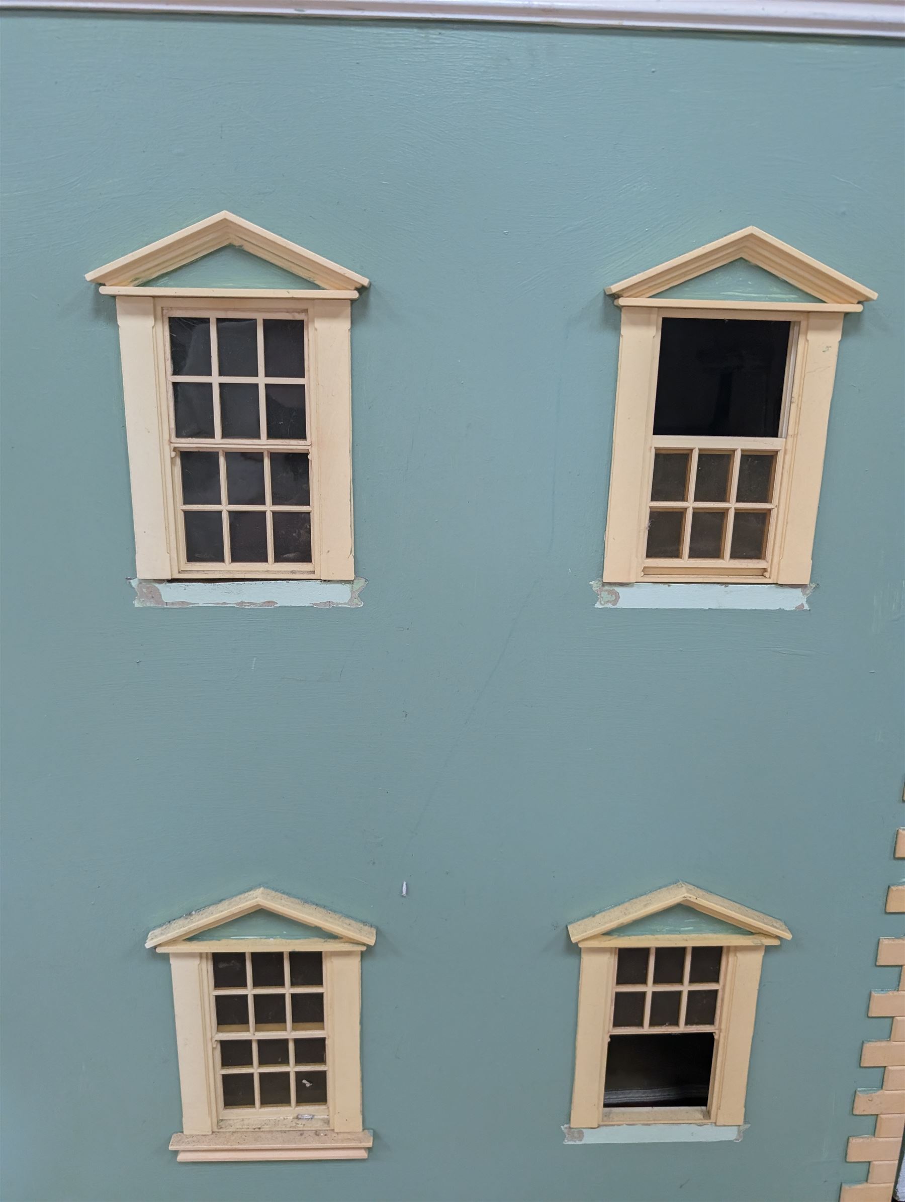Two modern three storey dolls houses, each painted green with decorated interiors, both upon a single white wooden base, together with a large collection of dolls house furniture, accessories and figures 