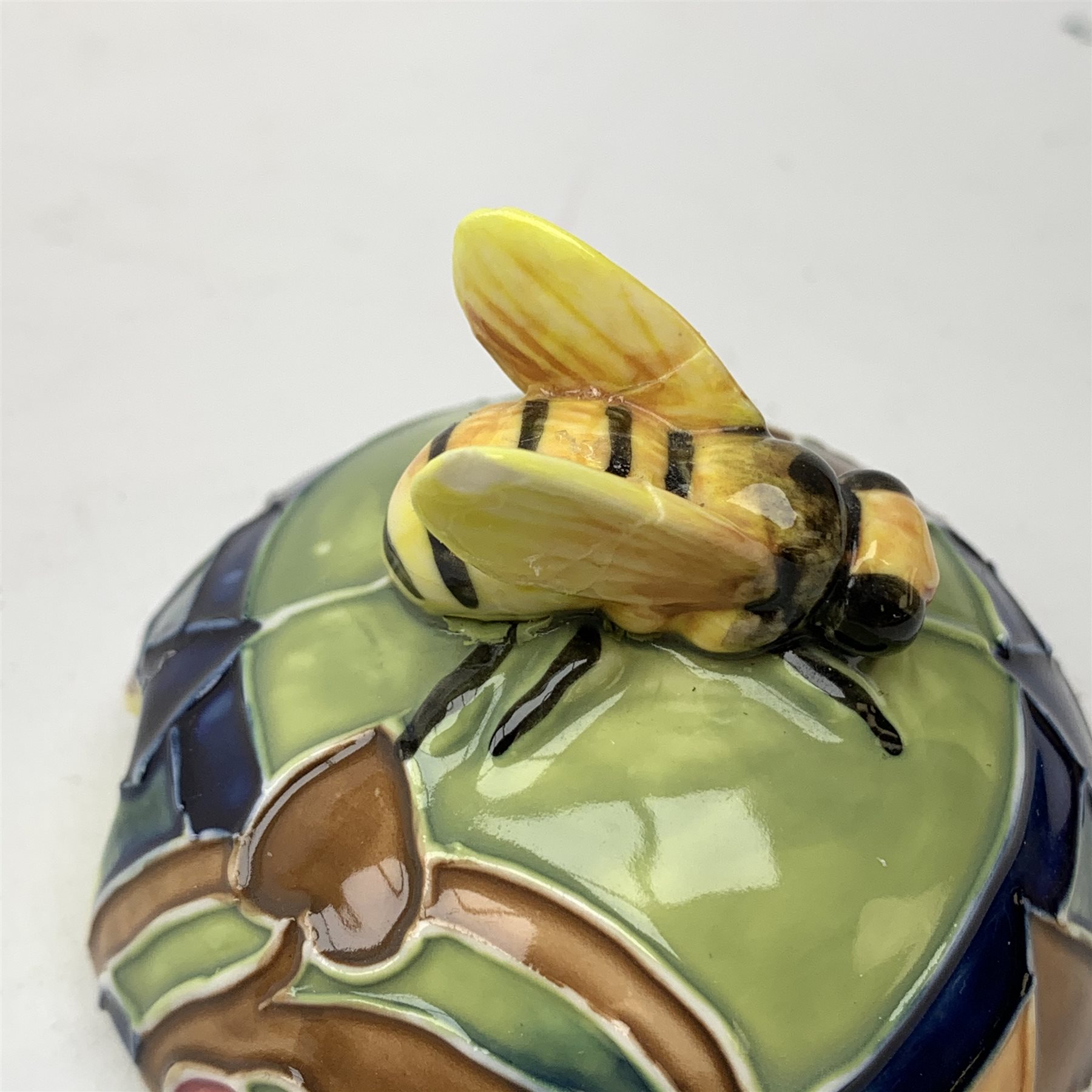 An Old Tupton Ware honey pot, of oval form with tube lined tendril decoration, the domed cover surmounted by a honey bee, with accompanying spoon, together with a pair of Old Tupton Ware vases, with tube lined sunflower decoration, H22cm, each with printed mark to base.