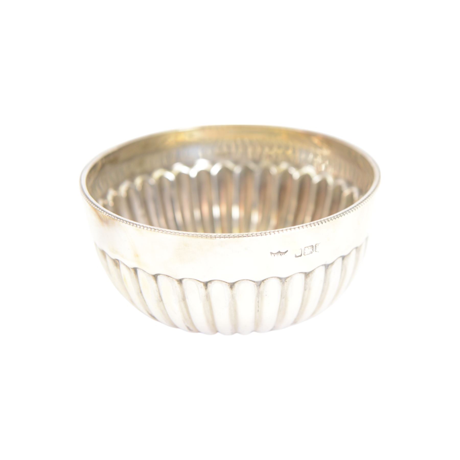 Edwardian silver shell butter dish, upon three bun feet, together with a matching shell spoon engraved with initial, both hallmarked Josiah Williams & Co, London 1906 and 1914, together with an Edwardian milk jug, open sucrier and sugar tongs, the jug and bowl of circular part fluted form with bead rim, hallmarked Mappin & Webb Ltd, Sheffield 1902, both sets contained within fitted tooled leather boxes with silk and velvet lined interiors