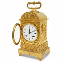 Fine Swiss ormolu 8-day early 19th century Pendule d'Officer style clock c1820,  circular double train ting-tang movement striking the quarters on a graduated pair of bells and sounding the hour on one, going train with a vertical platform lever escapement and over sprung balance, rack striking, with visible hour and quarter strike work to the backplate, movement unsigned, convex enamel dial with Roman numerals and steel moon hands behind a glazed gilt bezel, case with a scroll cast handle to the arched top with applied rococo decoration to the tympanum, both sides of the case adorned with a military trophy of arms motif and deep frieze with foliate arcading beneath, on a rectangular plinth with decorative scroll engraved bracket feet. With Key.   