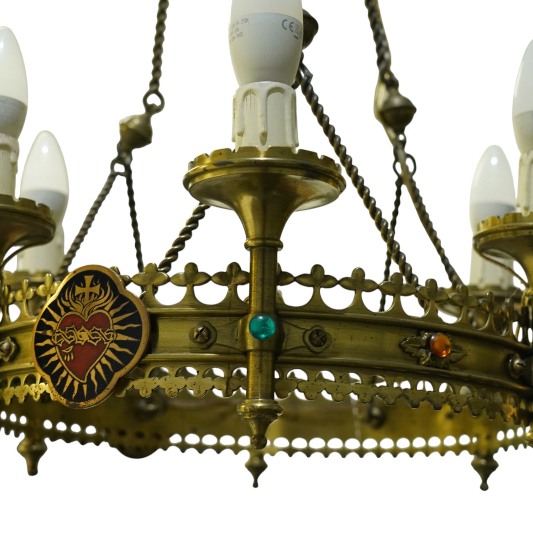 Gothic Revival brass six-light ecclesiastical chandelier, circular frame with pierced trefoil cresting and apron, applied with polychrome Sacred Heart medallions, six candle-form electric sconces, suspended on twisted brass rods and chains from a coronet-form ceiling boss