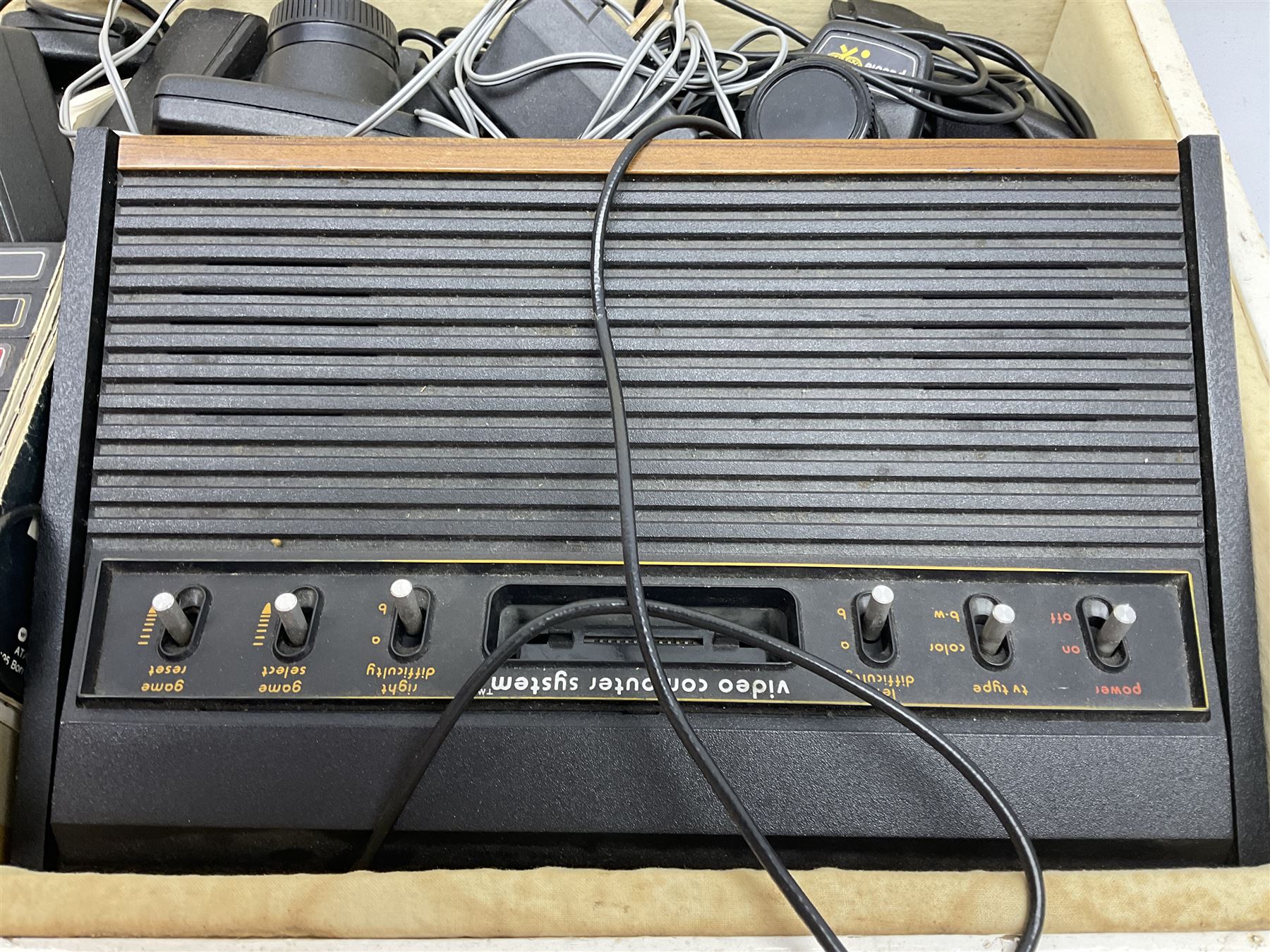 Atari 2600 'Woody' console with various joysticks and controllers etc, and a quantity of game cassettes to include 'Outlaw', 'Air Sea Seattle' and 'Codebreaker' etc housed in white painted wood case