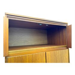 William Lawrence - mid-20th century teak double wardrobe, upper storage section over twin doors featuring recessed handles and contrasting horizontal panel, enclosing a hanging rail compartment, on plinth base with concealed castors