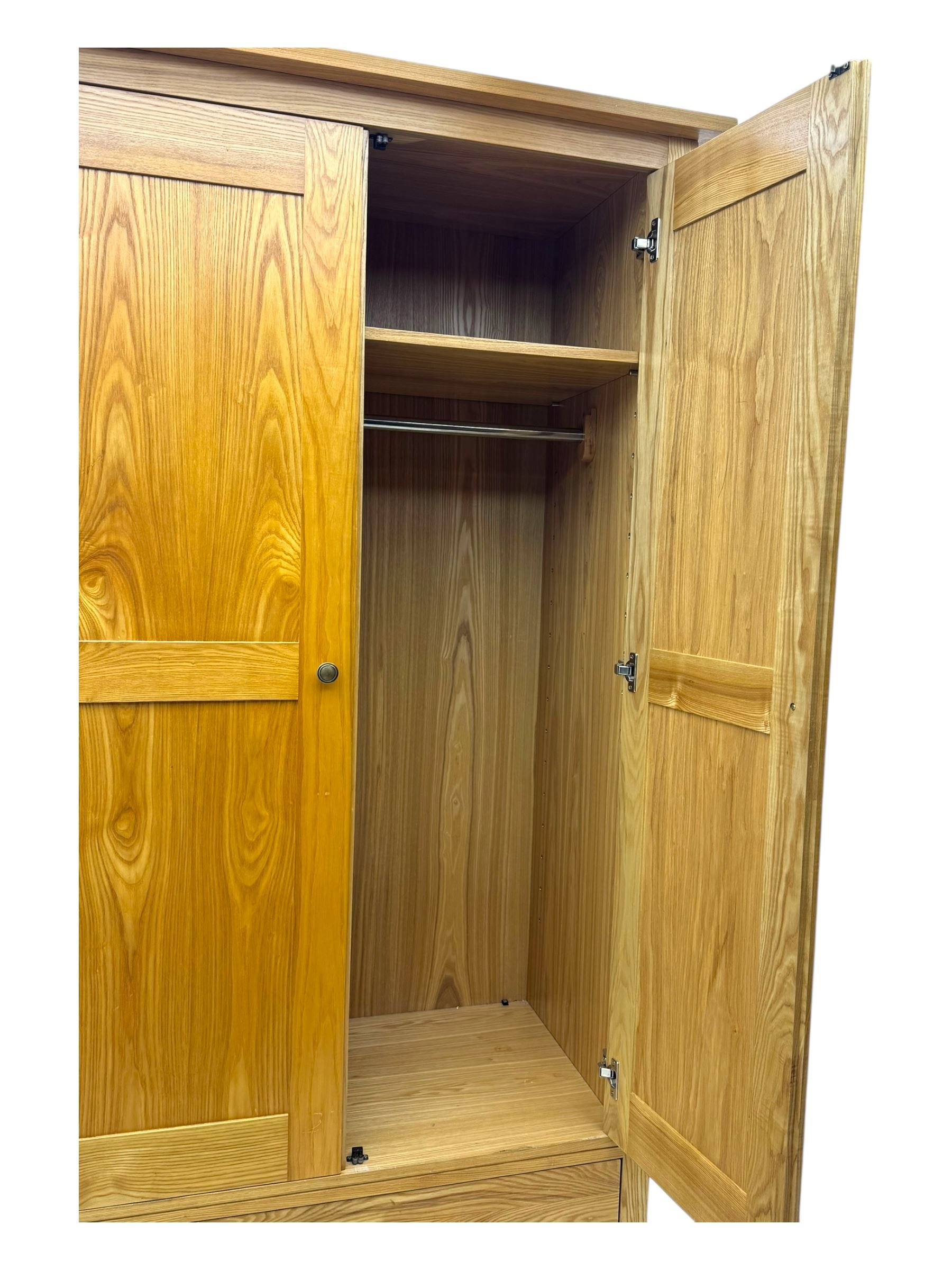 Contemporary light oak double wardrobe, projecting cornice over two panelled doors enclosing hanging rail and shelf, above full-width drawer, on shaped stile supports
