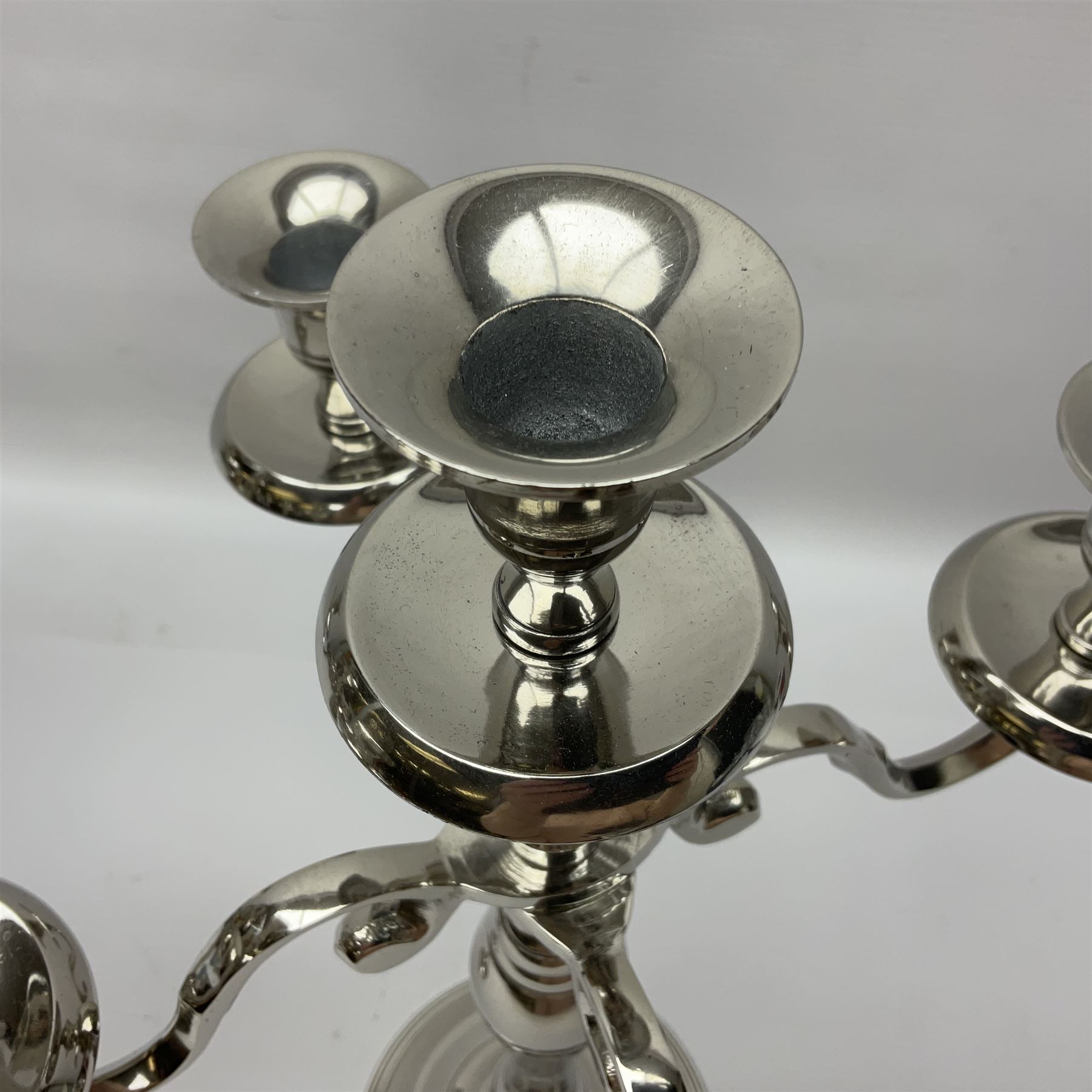 Pair of four branch candelabras, urn-shaped nozzles raised upon scroll branches supported from tapering central stem, with a stepped circular base, H40cm