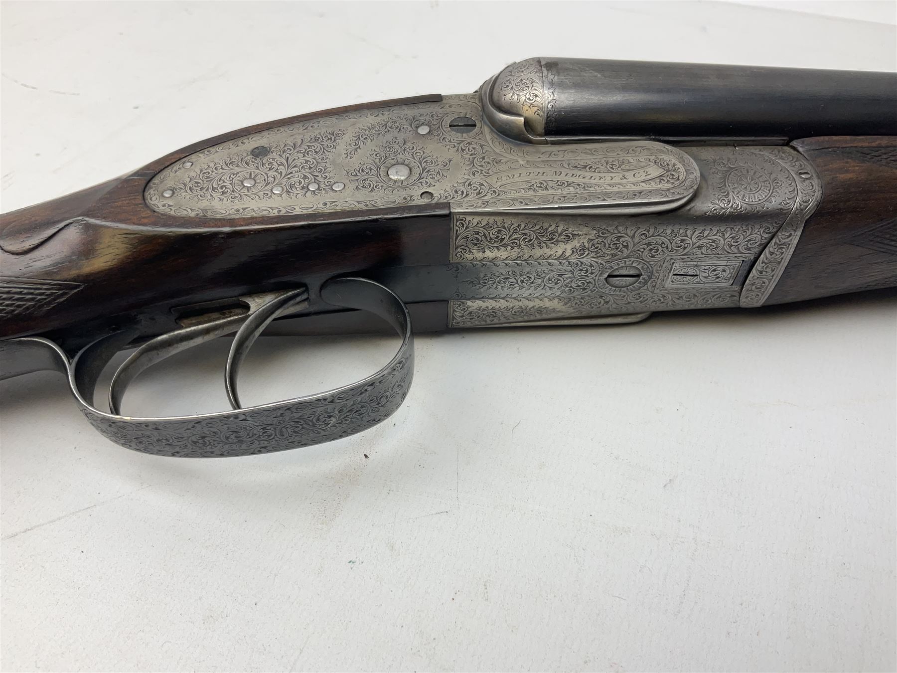 Smith Midgley Bradford 12-bore side-by-side double barrel side-lock ejector shotgun with 71cm barrels, engraved action with patented top lever, ivy leaf fences and top safety, walnut stock with chequered grip and fore-end, serial no.62409 to barrels and 1481 to action, L115cm overall SHOTGUN CERTIFICATE REQUIRED