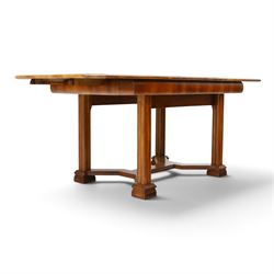 Art Deco walnut extending dining table, book-matched veneered shaped top, raised on cluster-column supports, united by stretchers, additional leaf extends to 185cm  