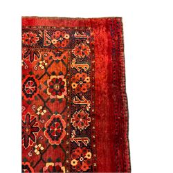 Persian red ground rug, the field decorated with lattice pattern and flowerhead, repeating border decorated with flower heads and leaf motifs