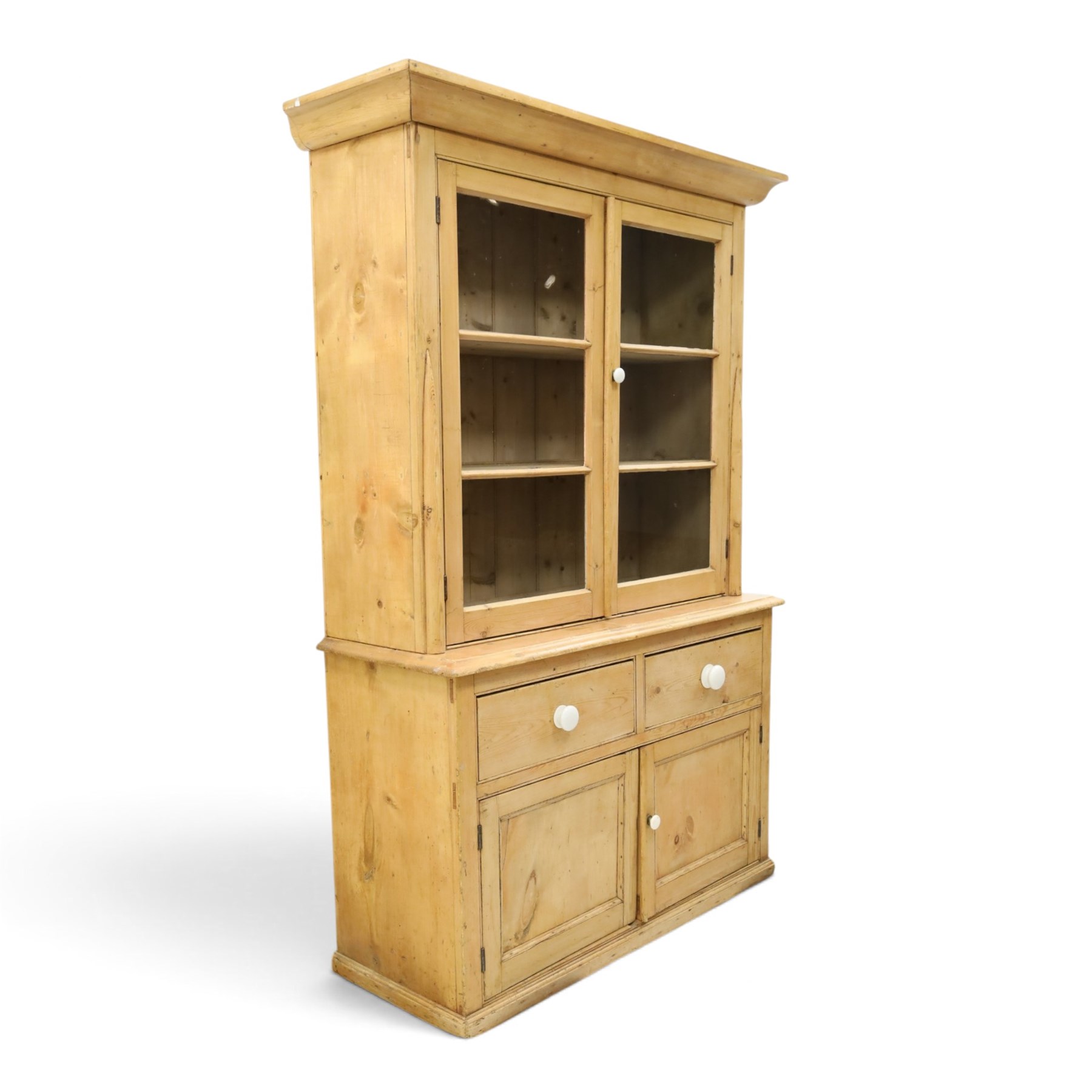 Victorian stripped pine and glazed dresser, projecting ovolo cornice over glazed doors enclosing two shelves, the base fitted with two drawers over panelled cupboards with ceramic handles, on moulded skirted base