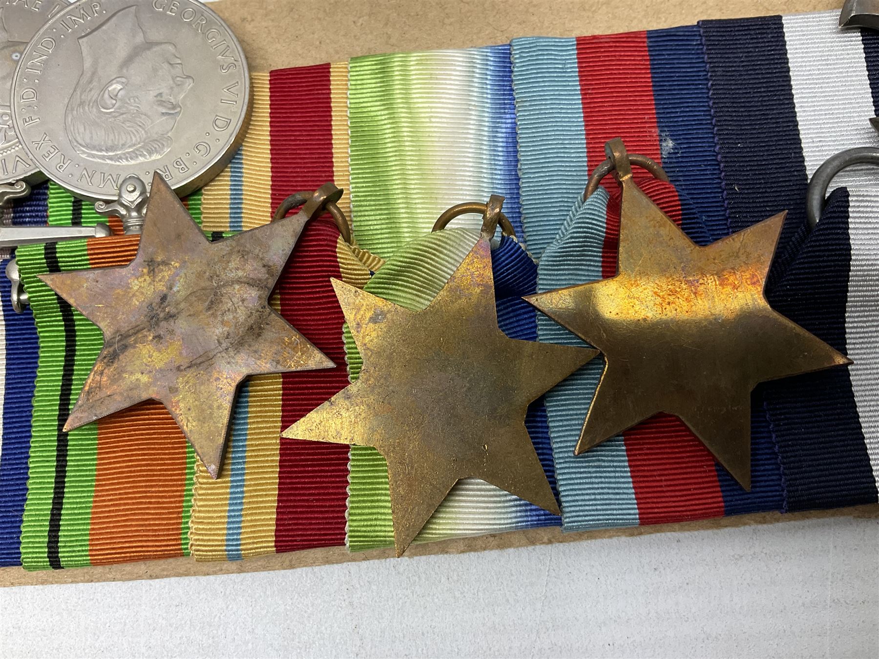 WW2 Royal Naval group of eight medals comprising OBE, hallmarked silver Distinguished Service Cross inscribed verso Lieut. J.R. McCluskie RNVR 1945, 1939-1945 Star, Atlantic Star, Africa Star, 1939-1945 War Medal, Defence Medal and Royal Naval Patrol Service Medal inscribed Lieutenant J.R. McCluskie Royal Naval Patrol Service; with seven original photographs of a sea battle 27th November 1940 against the Italian Fleet and another photographic postcard of Sir Stafford Cripps arriving on board one of the vessels.