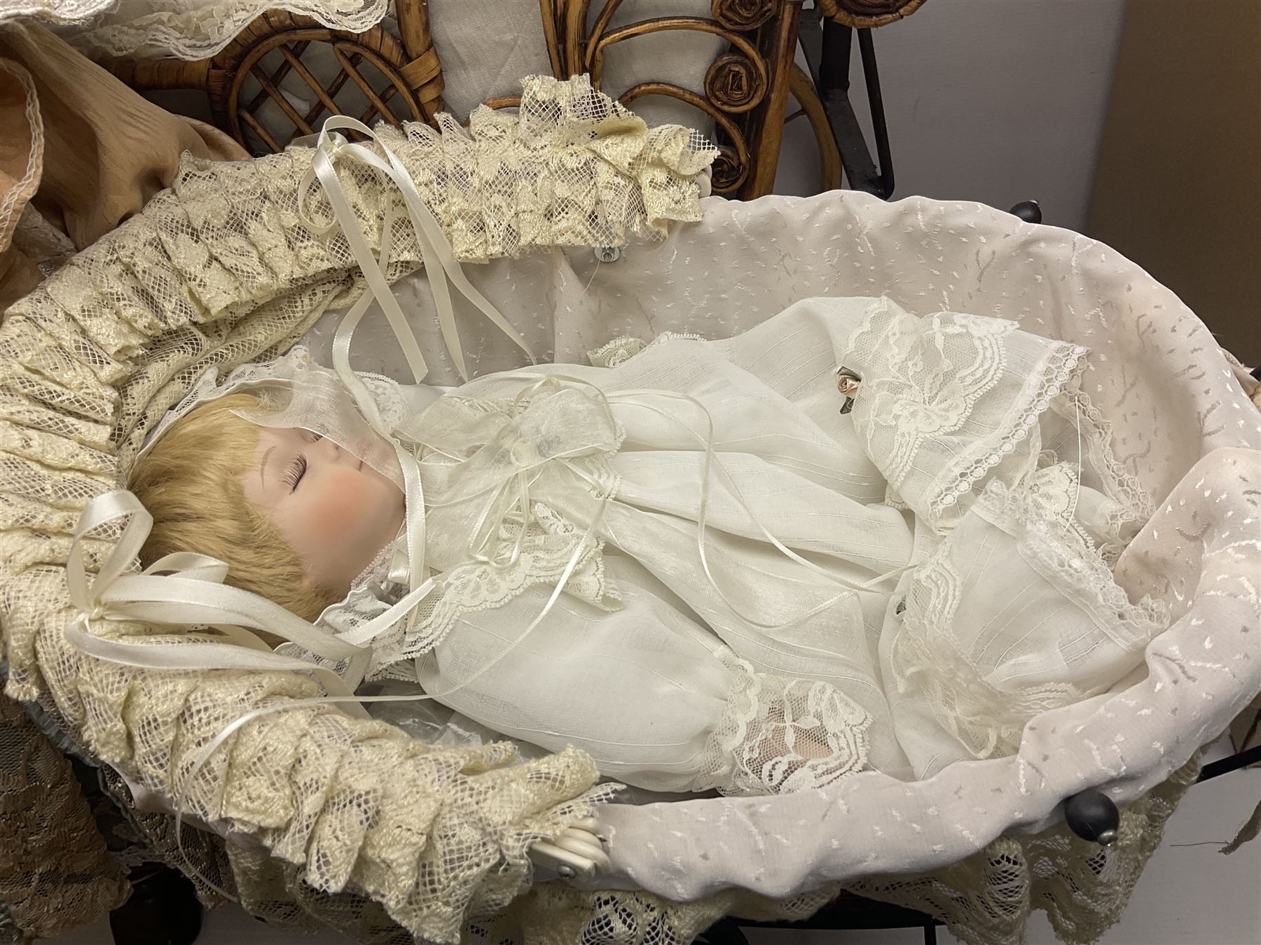 Two decorative wicker dolls prams, one with lace parasol,  and eleven dolls, including Leonardo Collection porcelain dolls, tallest pram including parasol H105cm