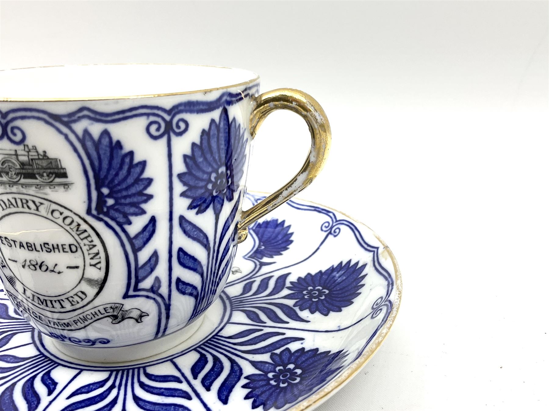 Late 19th century Coalport porcelain cup and saucer in the 'Aster' pattern bearing the crest of Express Dairy Company Limited, College Farm, Finchley and decorated with a steam locomotive