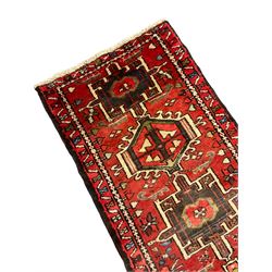 Persian Gharajeh runner, red ground and decorated with multiple medallions, all-over stylised flower head and geometric motif decoration, repeating border 