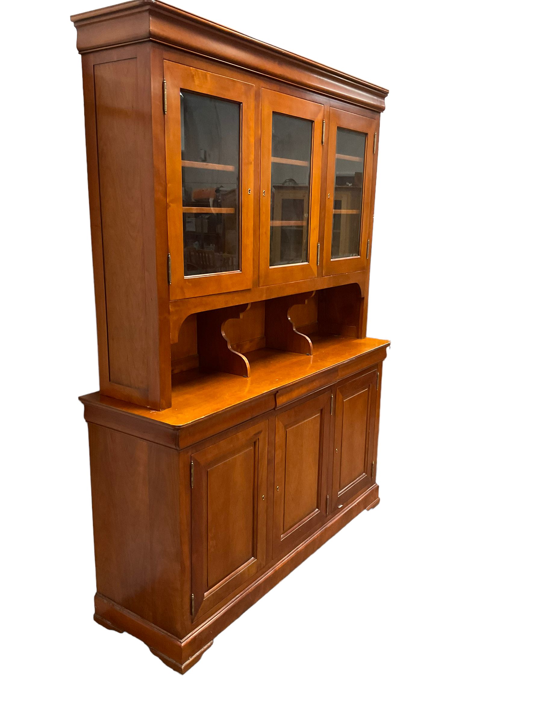 Multi-York -  Loire cherry wood dresser, shaped cornice over three glazed doors enclosing six shelves, the lower section fitted with three shallow drawers with shaped fronts over three cupboards with panelled doors, raised on plinth base with bracket feet