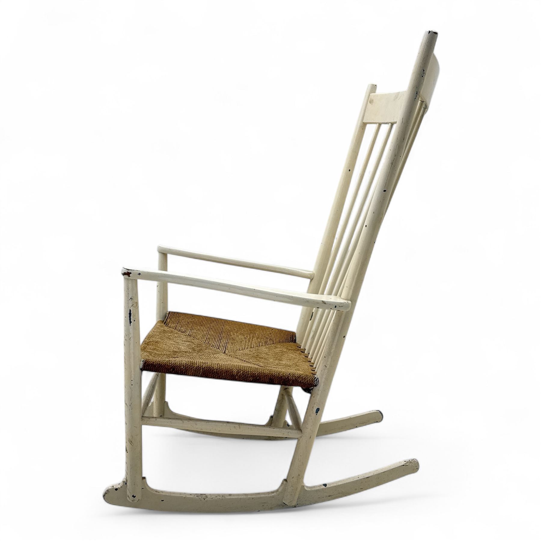 Mid-20th-century Scandinavian painted high-back rocking chair, curved top rail above slender spindle back, shaped arms with rounded ends above hand-woven rush seat, tapered rockers reinforced by turned stretchers 