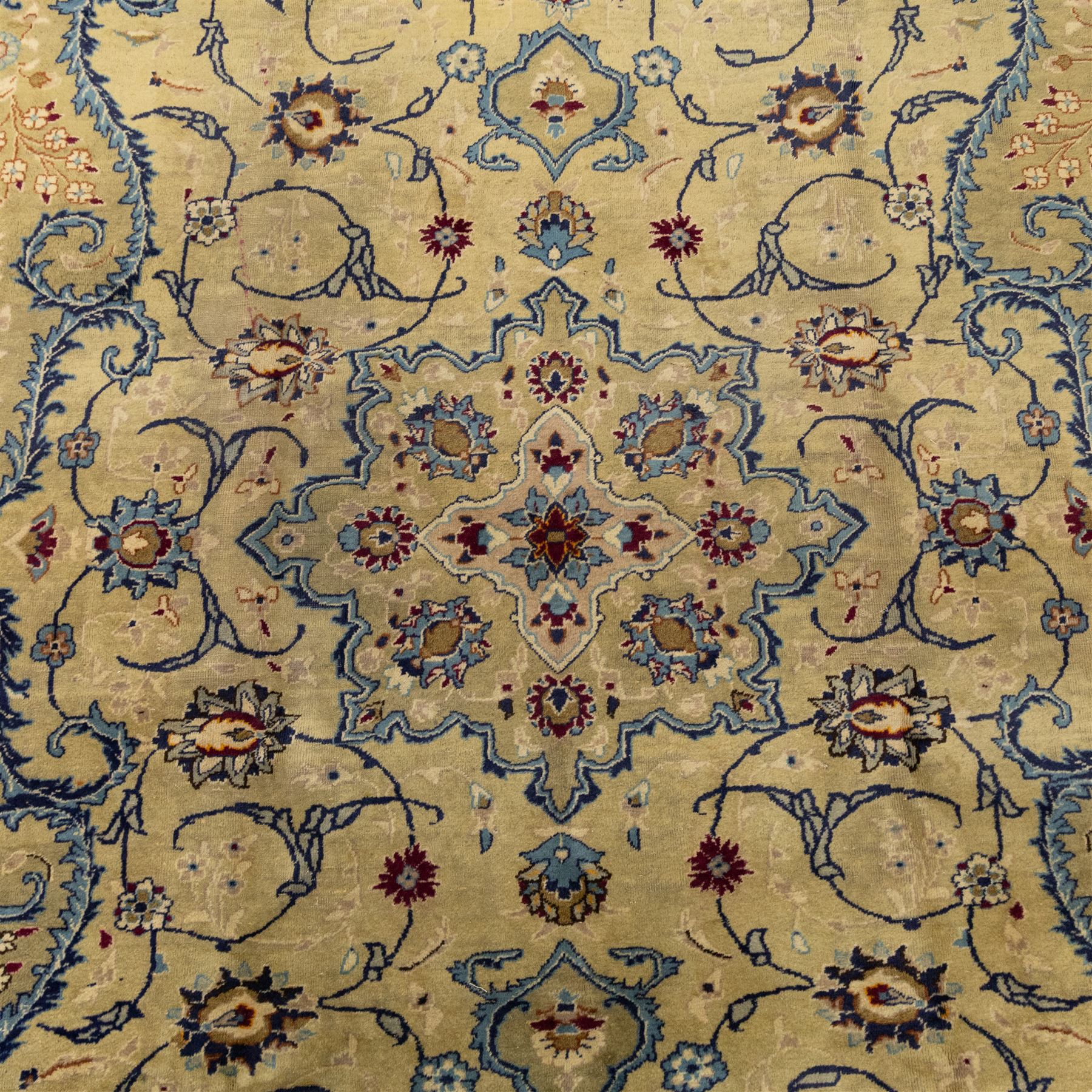 Central Persian Kashan hand-knotted carpet, ivory field with central shaped medallion, surrounded by intricate arrangement of scrolling vine and floral motifs in  pale blue tones, within conforming spandrels and matching border, cotton fringe ends  