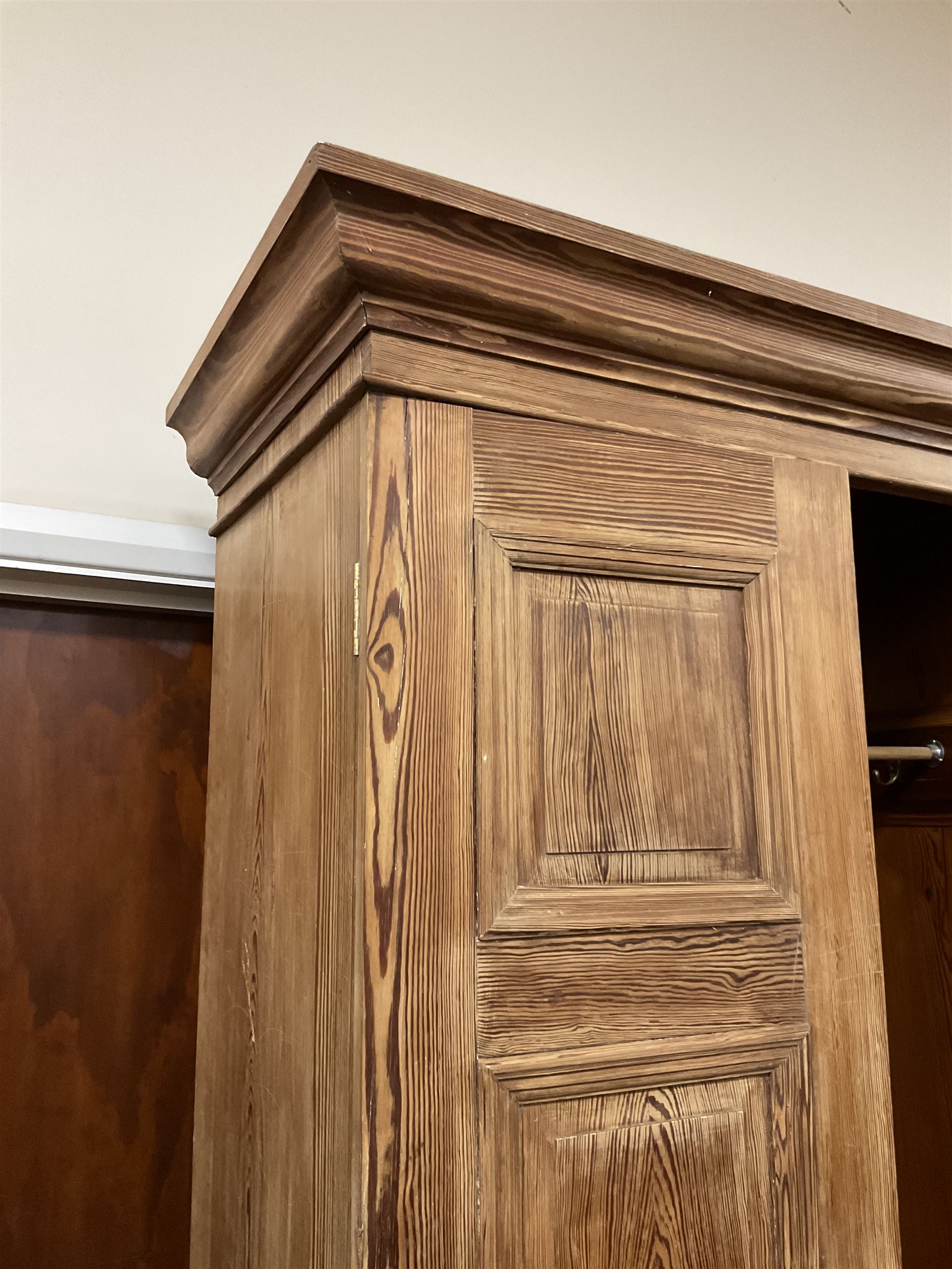 Victorian pitch pine double wardrobe, projecting moulded cornice over two panelled doors, the interior fitted with hanging rail and hooks, single drawer to base