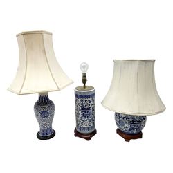 Three oriental table lamps decorated with blue and white floral design, two with fabric shades, all on turned wood bases, tallest incl shade H66cm