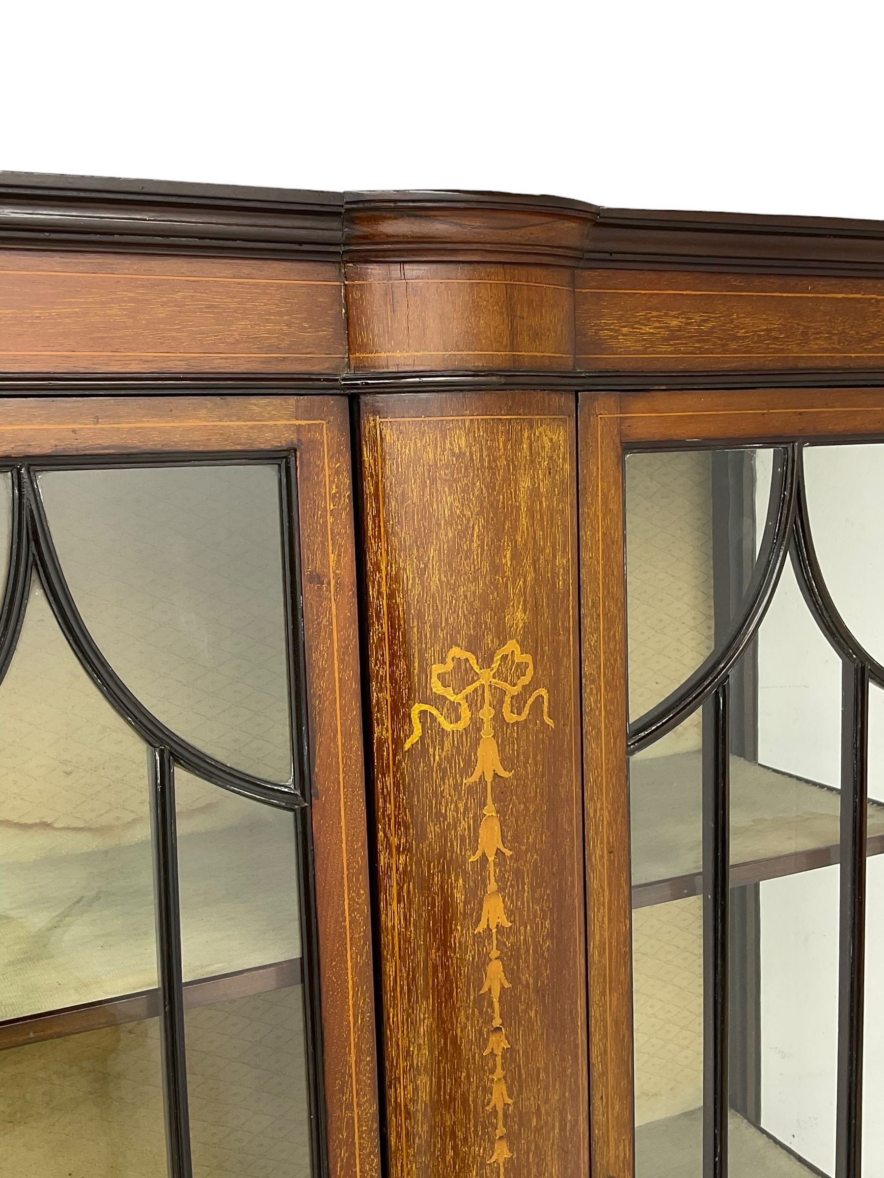 Edwardian inlaid mahogany display cabinet, enclosed by two astragal glazed doors, bowed centre inlaid with ribbon and trailing bellflowers, on square tapering supports with spade feet united by undertier 