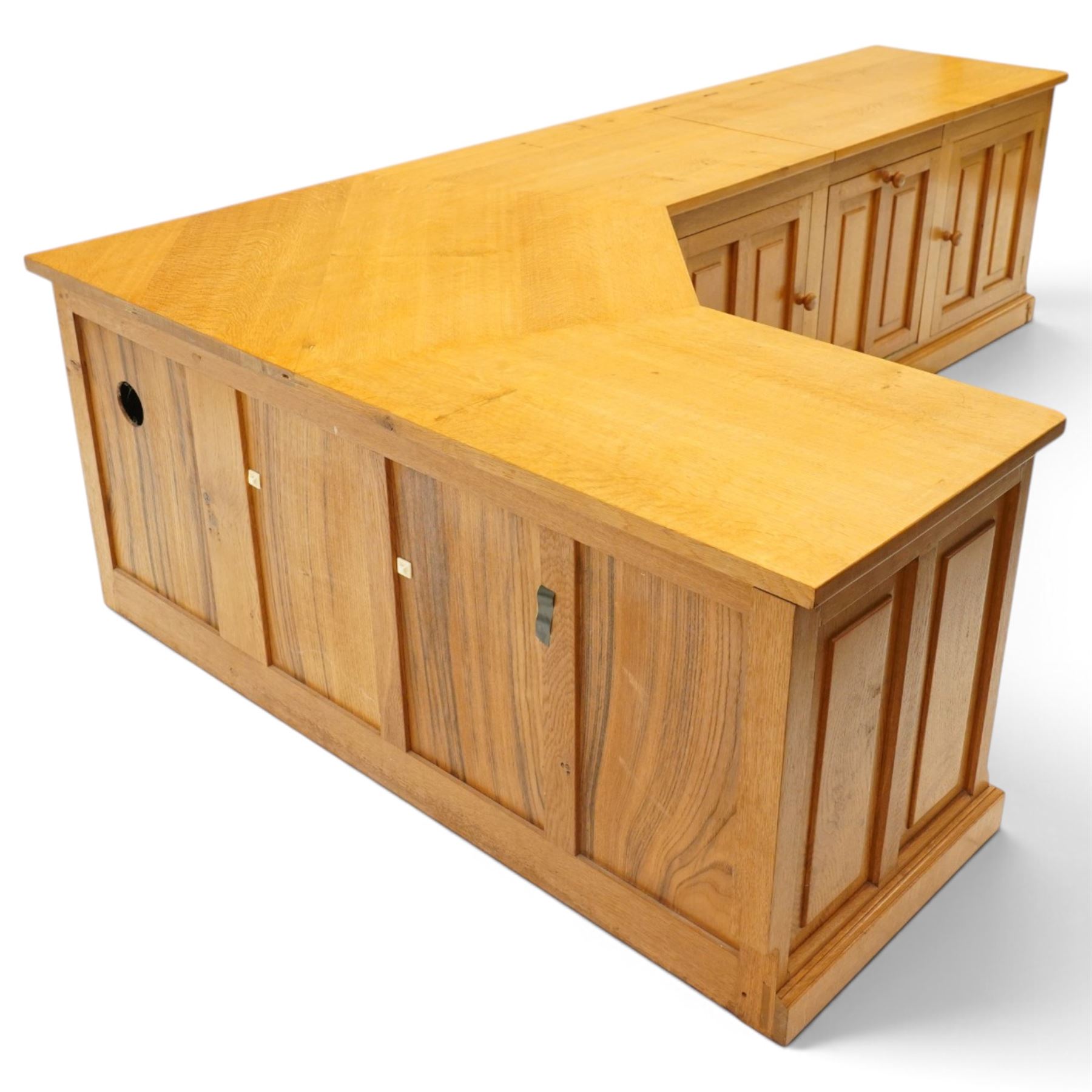 Seahorseman by Shaw & Riley - bespoke large Yorkshire oak corner sideboard or media unit, of L-shape form, with three cupboard doors, a fall front drawer over a regular drawer, a lift up panel for a record player, multiple apertures for wires, raised on a plinth base, with signature Seahorse carving from the workshop of A. Shaw & Riley Ltd, Hessay