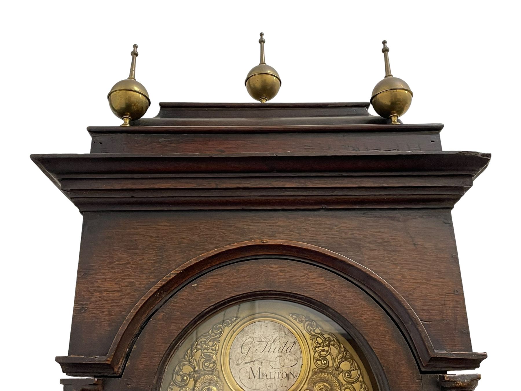 Gilbert Kidd of Malton (North Yorkshire) - late 18th century oak 8-day longcase clock c1780,  with a tall double caddy top and later brass ball and spire finials, break arch hood door beneath with attached pilasters and wooden capitals,  plain trunk with a long flat topped door, raised on a square plinth with applied skirting,  brass break arch dial with the makers name to the silvered boss in the break arch, engraved and silvered dial centre and chapter ring, with cast spandrels and matching steel hands, subsidiary seconds dial and square calendar aperture, dial pinned directly to a rack striking movement with a recoil anchor escapement, sounding the hours on a cast bell. With pendulum and weights.
The Kidd family were a prolific family of provincial clockmakers working in Malton from the mid 18th century until the early 19th century. Many of their clocks are simply signed 