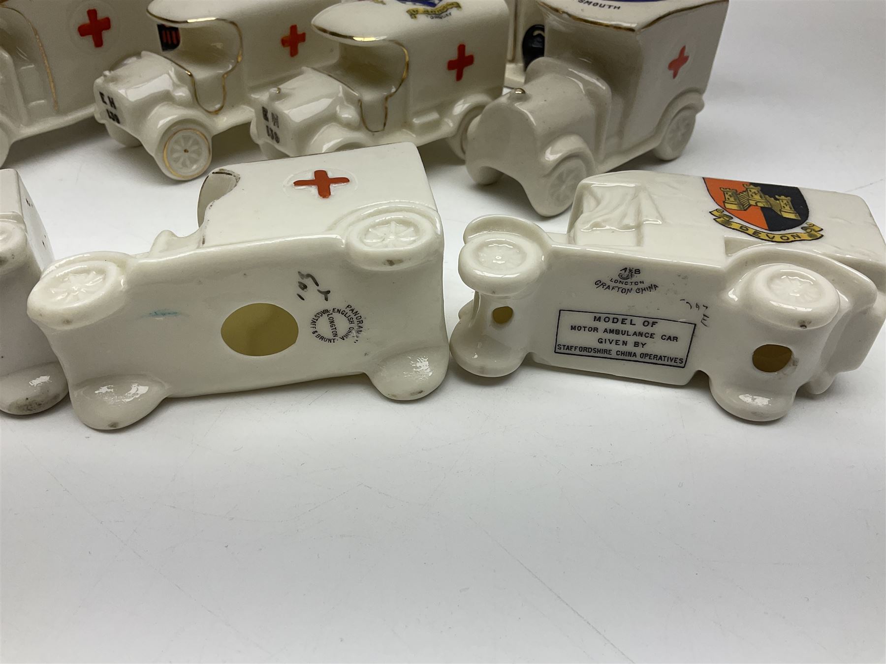 Ten WW1 crested china military models comprising seven field ambulances and three 'Home Fires Burning' fire-surrounds/range; various makers including Willow Art, Arcadian China, Grafton China, Savoy China, Carlton China etc; various crests including Devon, Aldershot, Portsmouth, West Ham, Coventry, Oxford, Hastings, Brighton etc (10)