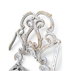 Pair of Victorian cast iron garden chairs, the ornate pierced back of scrolling foliate design, scrolling arm terminals over splayed supports formed of C and S-scrolls, in distressed white painted finish