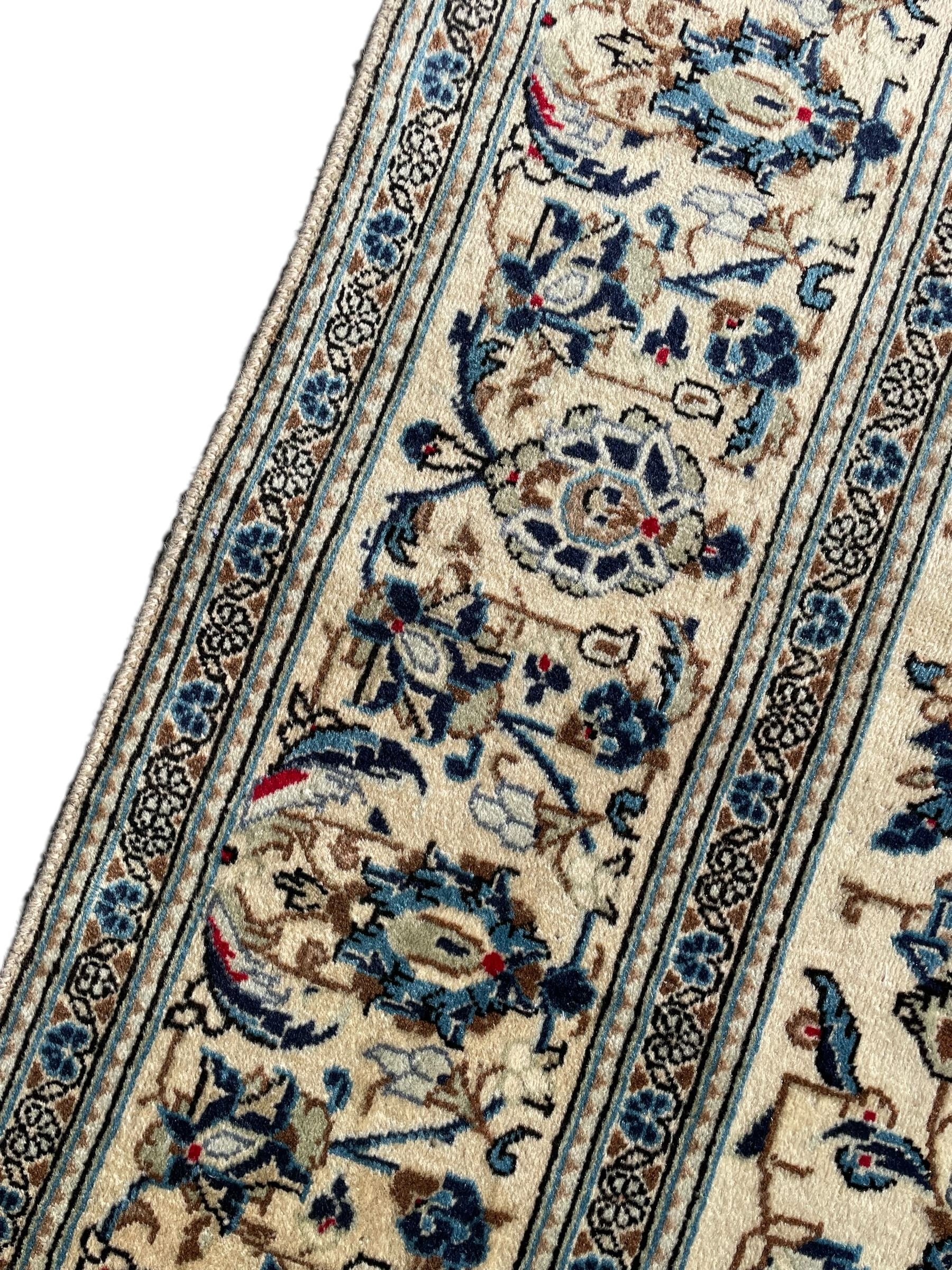 Persian Kashan ivory ground rug, the field decorated with trailing branches with leaves and palmettes, similar scrolling border, within floral pattern guard stripes 