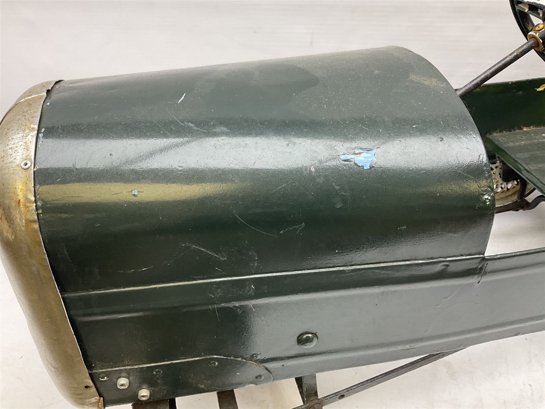 Mid 20th century pressed steel pedal car, the body painted in dark green fitted with pretend radiator to the bonnet, with spoked wheels and rubber tyres, the interior with pedals and steering wheel, L70cm