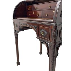 Georgian design mahogany writing desk, fretwork gallery over cylinder roll top, the curved ends carved with trailing bellflowers, fitted with a combination of small interior drawers with bone lozenge escutcheons, sliding top with hinged and adjustable inset leather writing surface, arched kneehole carved with trailing floral branches flanked by two cock-beaded drawers with foliage cartouches, C-scroll carved corner brackets, on tapering supports decorated with trailing bellflowers terminating to block feet 