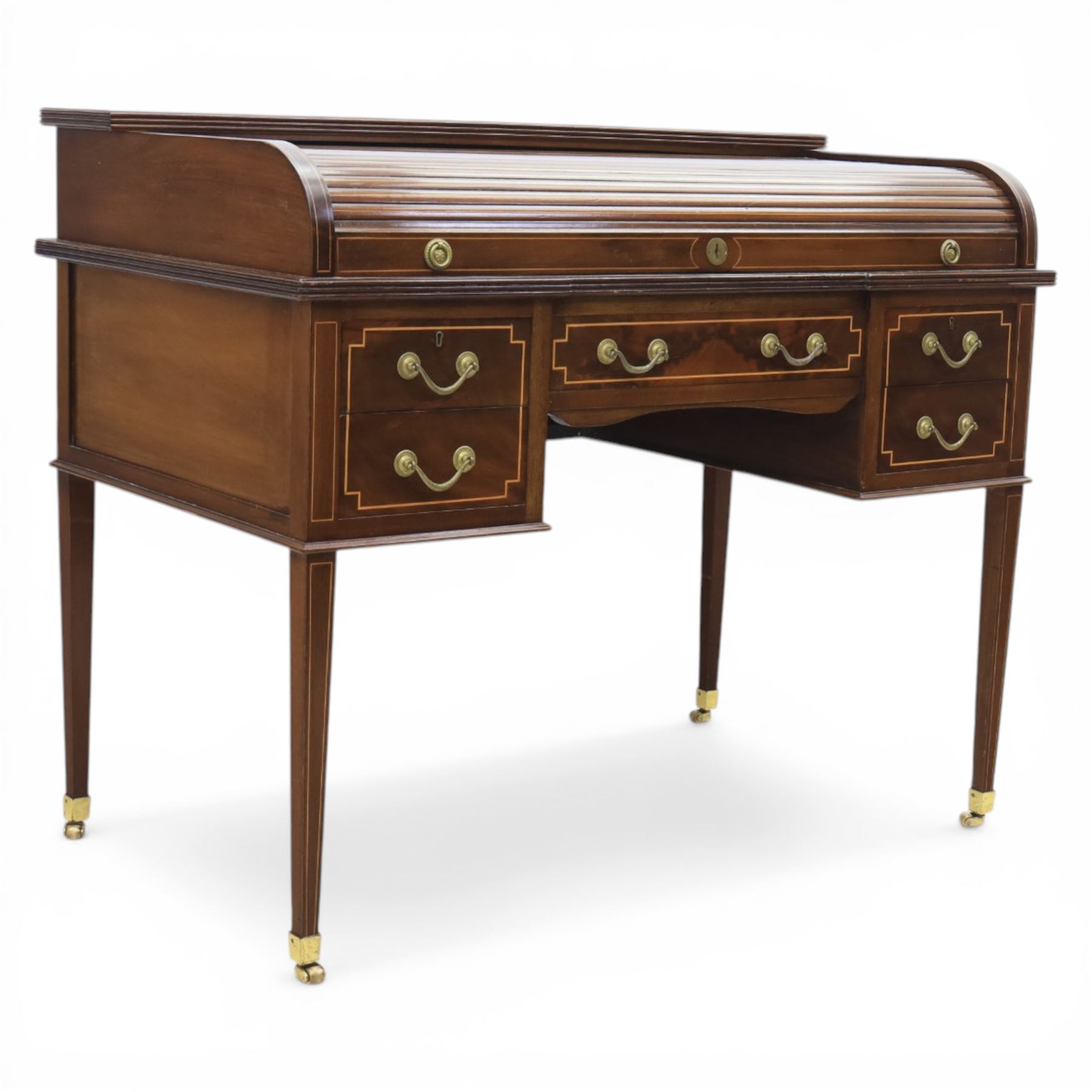 George III style inlaid mahogany tambour desk, the roll top enclosing fitted interior with small drawers and compartments above inset leather writing surface, over three frieze drawers, raised on square tapering supports with brass caps and castors