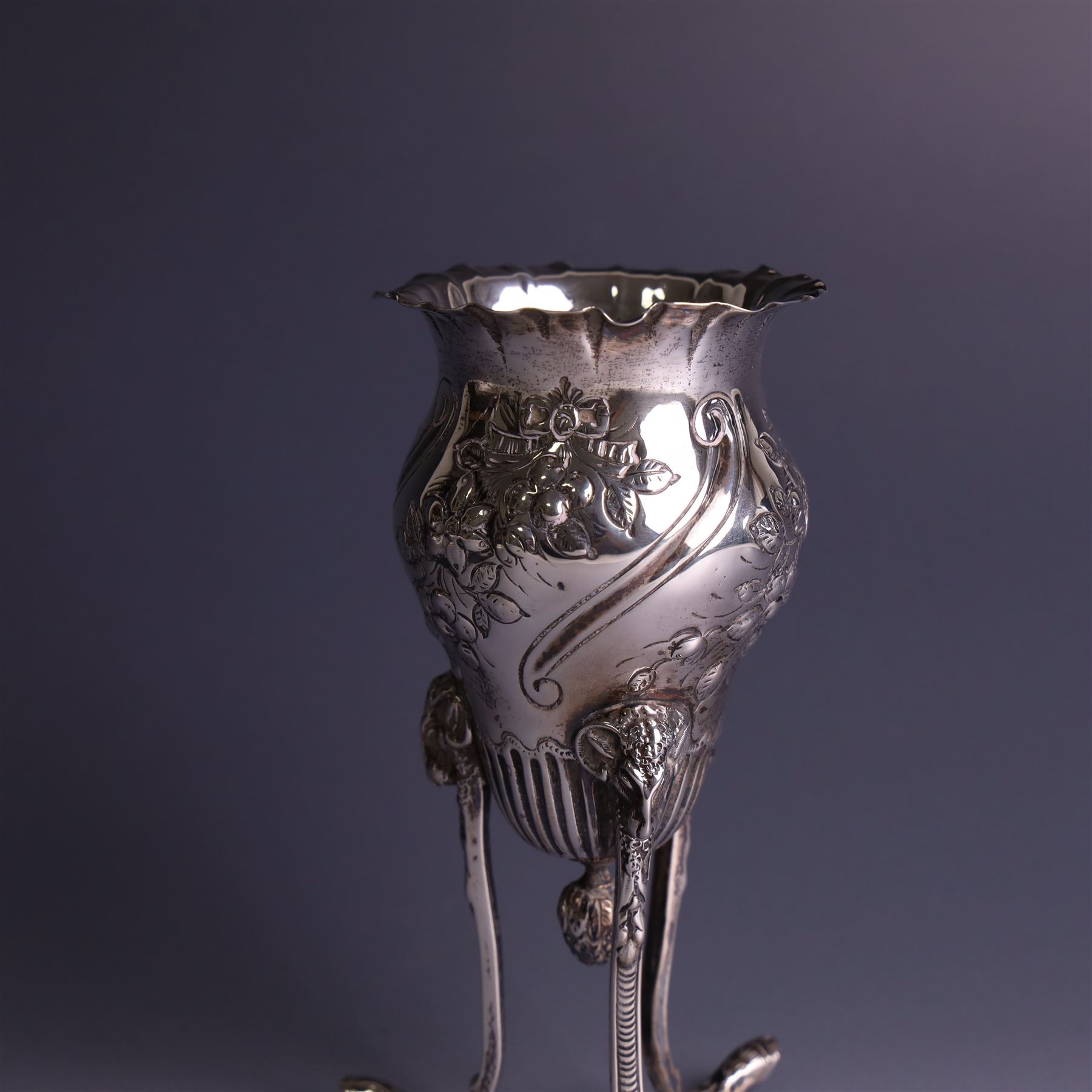 Late Victorian silver vase, of baluster form with fluted rim, the body with embossed floral decoration, upon three tall legs with ramshead mounts, hallmarked William Comyns & Sons, London 1890, H13.5cm