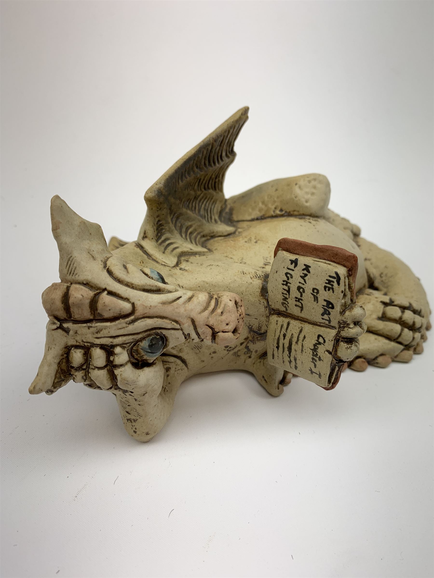 Zell Osbourne (British, Contemporary), Bookworm, a Studio Pottery figure modelled as a recumbent dragon with book, L21cm. 