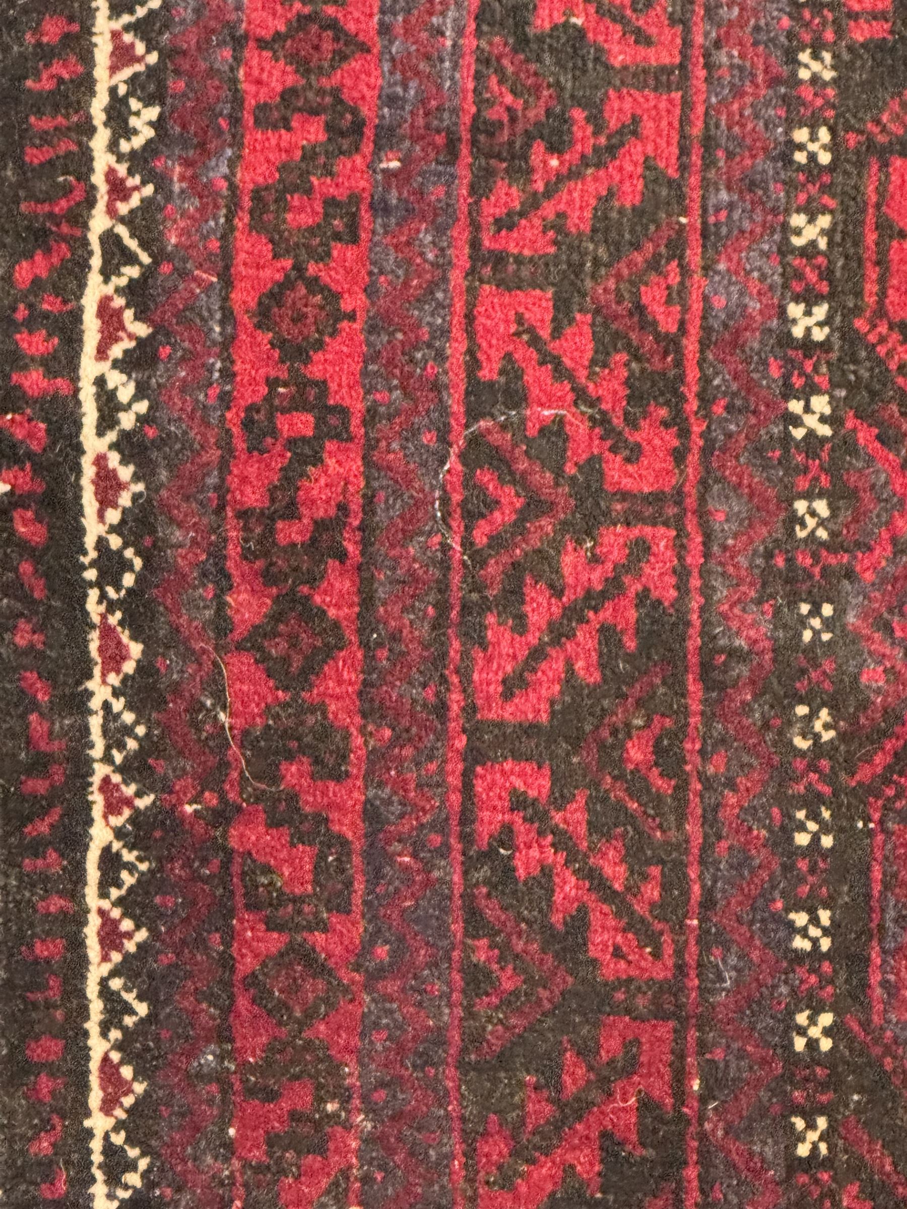 Turkoman red ground wool rug, the field with a repeating pattern of Tekke gul motifs in dark brown and red (195cm x 98cm); Afghan Bokhara red ground wool rug, central field with repeated geometric octagonal gul motifs, surrounded by multiple borders with stylised diamond and triangular patterns (127cm x 181cm)