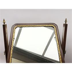 Georgian mahogany swing toilet mirror, the rectangular plate with gilt slip and moulded frame, supported on tapering horns with brass finials, upon a base with shaped front fitted with three drawers, and ogee bracket feet, H54cm W38cm D21cm