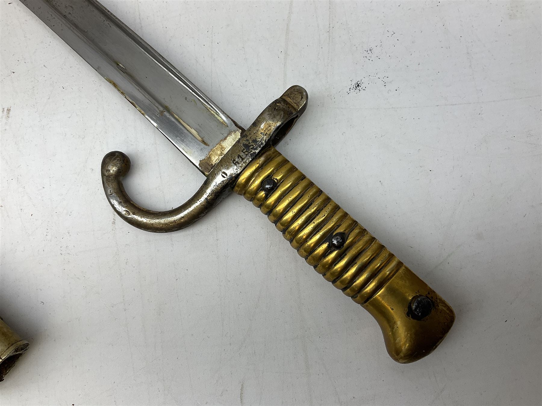 French Model 1866 sabre bayonet with 57cm fullered steel curving blade; in steel scabbard L71cm overall; another Model 1866 sabre bayonet lacking scabbard; and British Pattern 1856 sword bayonet (no scabbard) (3)