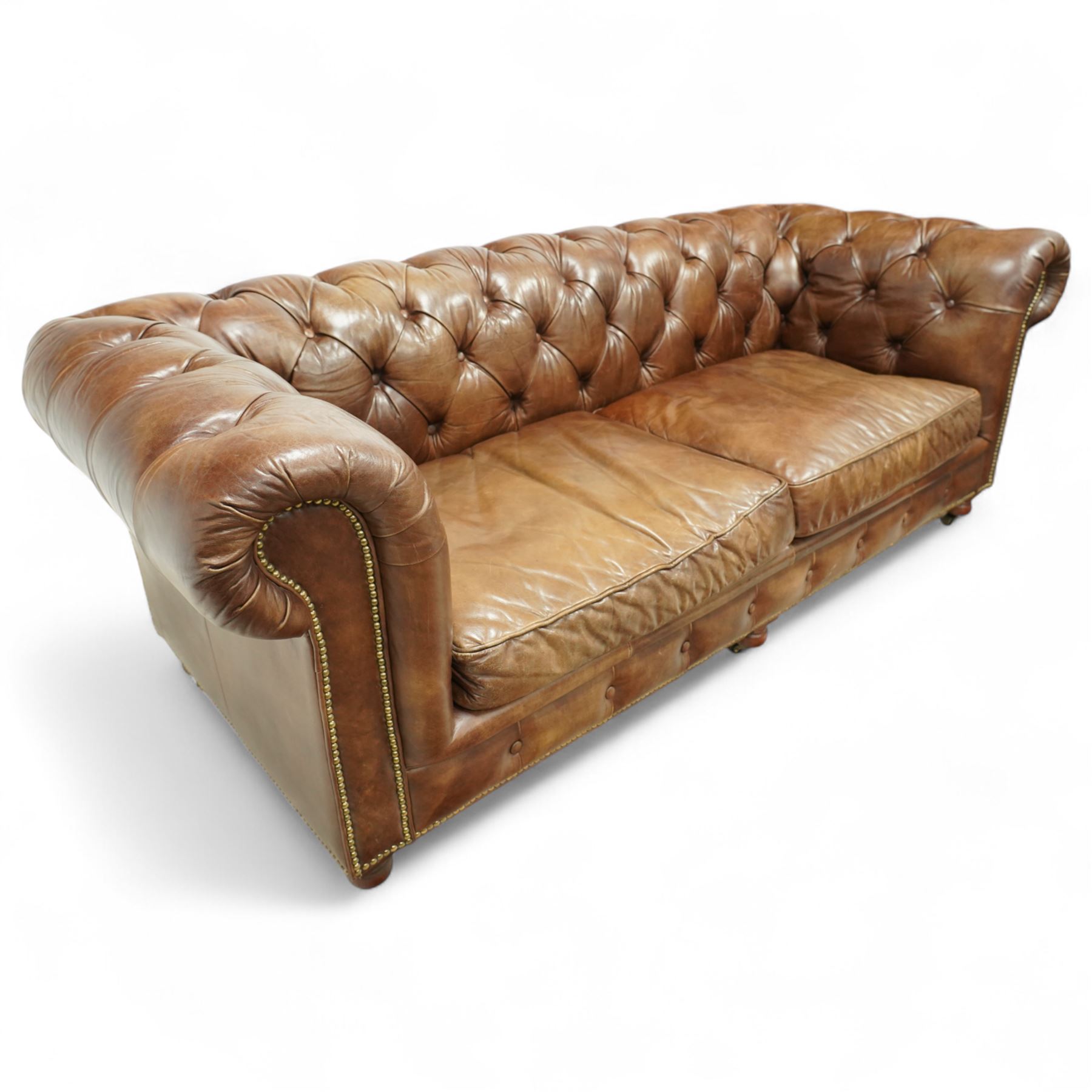 Timothy Oulton, Halo - Late 20th century brown leather Chesterfield settee, the upholstered frame with deep buttoning to back and arms, large scroll terminals with brass studwork, twin seat cushions, raised on castored legs